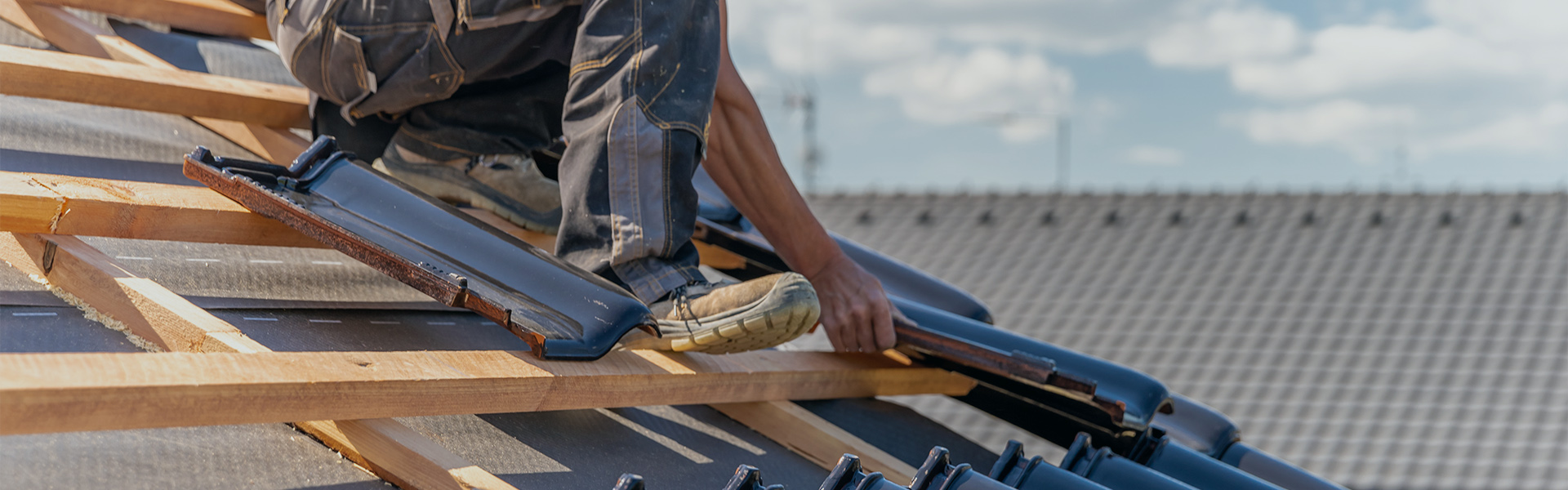 Dachdecker sitzt auf Dach mit Schindel in der Hand